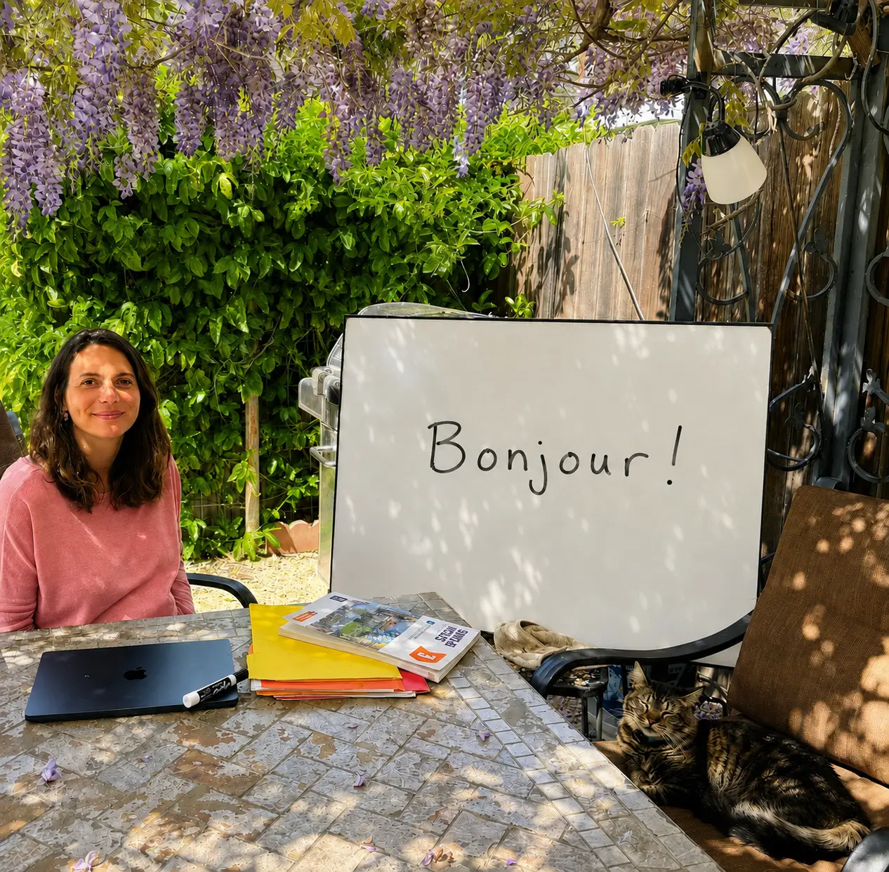 Wanda in her garden classroom beside a whiteboard reading Bonjour